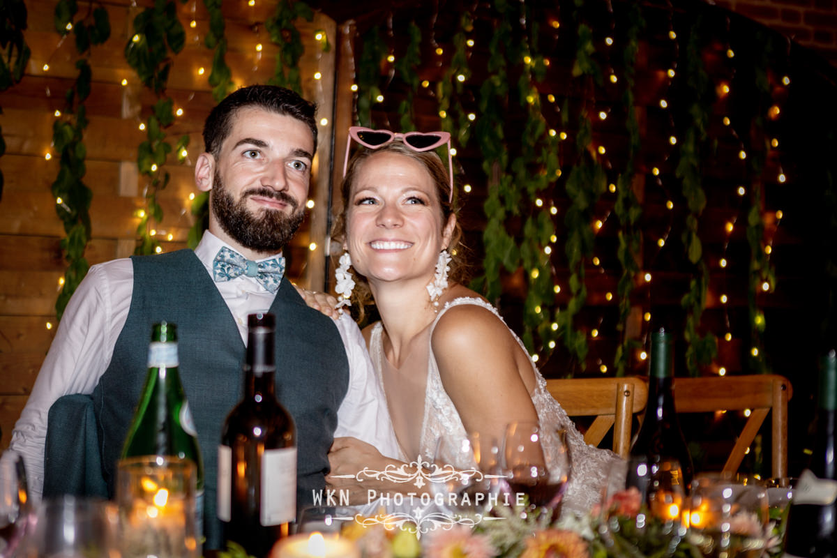 Claire et Corentin rayonnent de bonheur pendant la réception, sourires aux lèvres et entourés de leurs invités.
